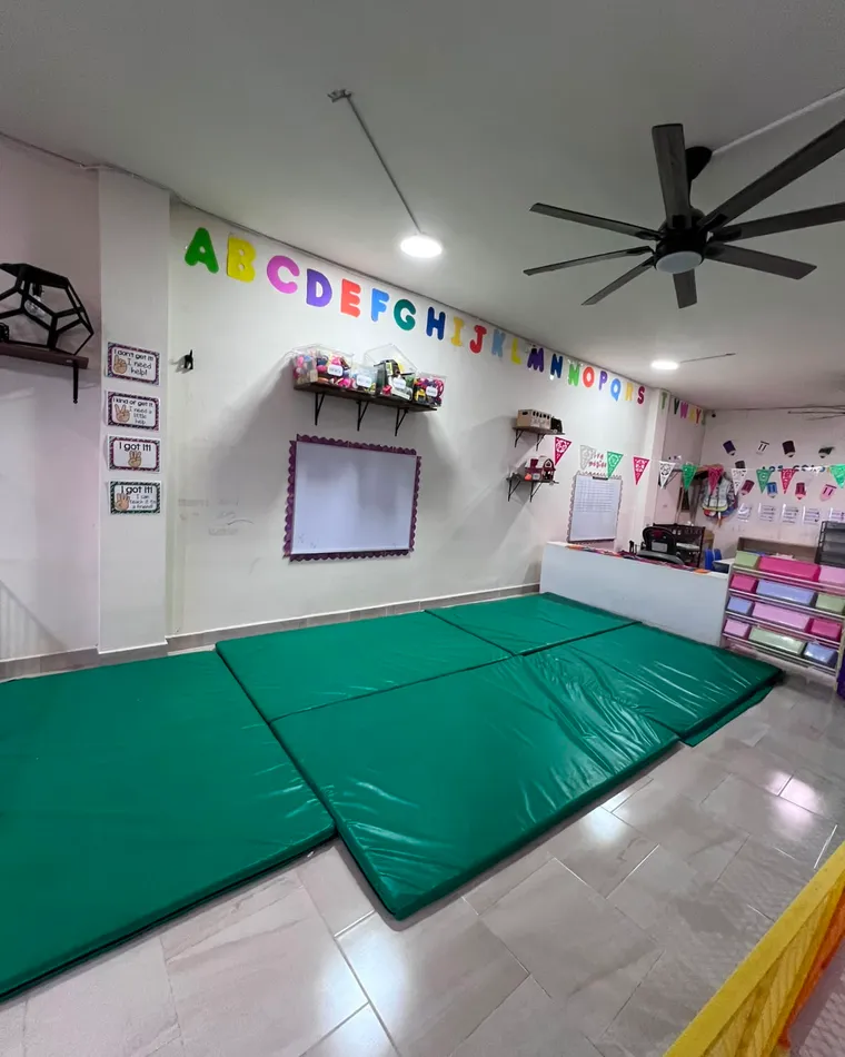 Sala con colchonetas verdes extendidas en el piso.